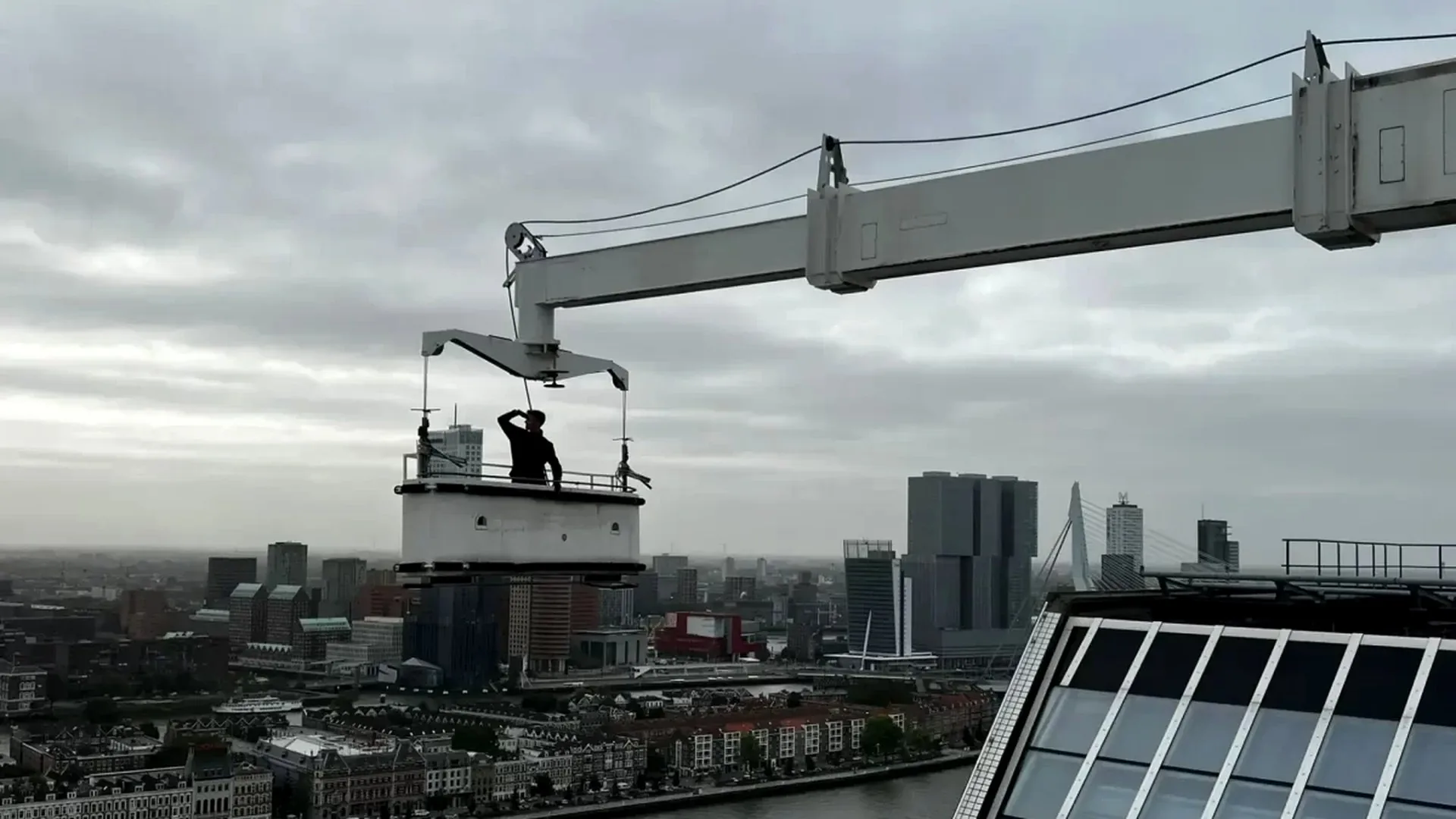 Monteurs van Oude Tanke Techniek op een gondel boven de skyline van Rotterdam
